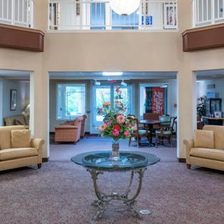 A cozy lobby area with sofas and a glass table featuring a floral arrangement.