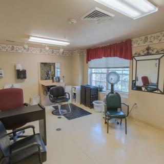 A cozy salon interior featuring chairs, mirrors, and a hair dryer near a window.