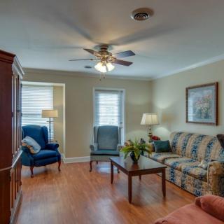 A cozy living room with a sofa, chairs, coffee table, ceiling fan, and wooden flooring.