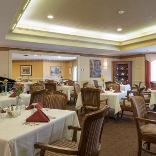 An elegant dining room with neatly arranged tables and chairs, set for guests.