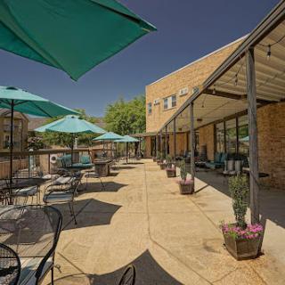 A serene outdoor cafe area featuring teal umbrellas and comfortable seating, perfect for enjoying a sunny day.