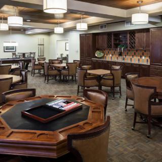 A spacious room with wooden tables and chairs, featuring warm lighting and elegant furnishings.