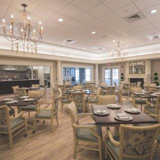An elegant dining room with neatly set tables and chandeliers.