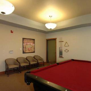 A cozy billiard room featuring a red pool table and seating area.