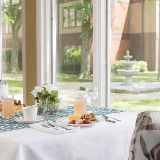 A cozy breakfast table set near a window with a view of a courtyard fountain and greenery.