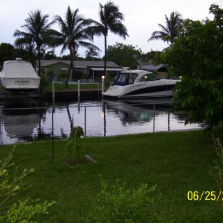 A serene canal view with boats docked and palm trees in the background.