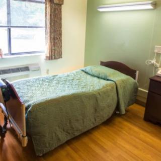 A simple, well-lit bedroom with a single bed and a window.