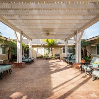 A spacious patio with a pergola and comfortable seating arrangements, bathed in sunlight.
