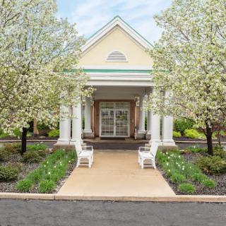 A serene entrance surrounded by blooming trees and a well-maintained garden.
