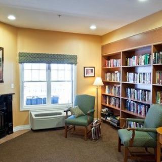 A cozy reading area with bookshelves, chairs, and a window letting in natural light.