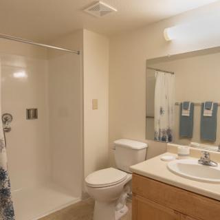 A modern bathroom featuring a shower, toilet, and sink with neatly arranged towels.