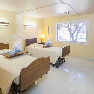 A well-lit hospital patient room featuring two beds, designed for comfort and care.