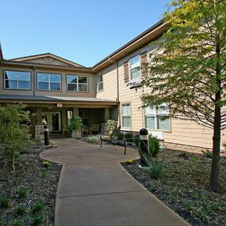 A residential building with a landscaped entrance and a winding pathway.