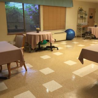 A room with tables and chairs, featuring a window with blinds and an exercise ball in the corner.