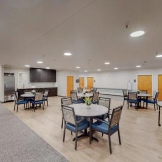 A modern indoor dining area with tables, chairs, and a television.
