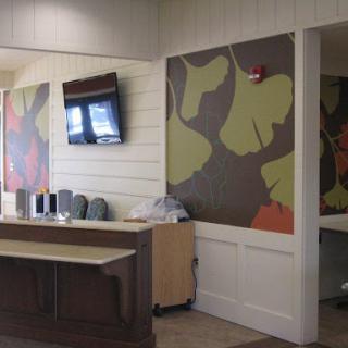 A modern office reception area featuring colorful wall art and a television.