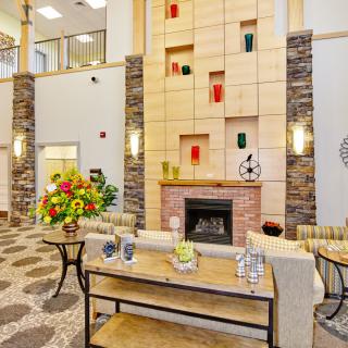 A modern lobby featuring a central fireplace, colorful artwork, and elegant decor.