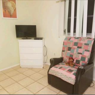 A cozy corner of a living room featuring a comfortable chair, a television, and a dresser.