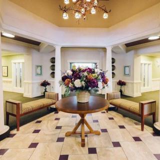 A welcoming lobby with elegant decor, featuring a central table with a floral arrangement and benches for seating.
