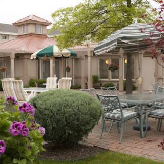 A well-maintained outdoor patio area with tables, chairs, umbrellas, and blooming flowers.