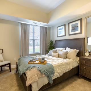 A well-decorated bedroom featuring a comfortable bed, elegant furniture, and soft lighting.