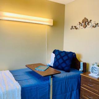 A cozy bedroom setup featuring two beds with blue bedding, a wooden dresser, and warm lighting.