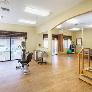 A spacious physical therapy room equipped with various exercise machines and open areas for rehabilitation activities.