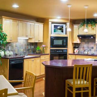 Modern kitchen with wooden cabinets, island seating, and stylish pendant lighting.