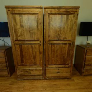 A pair of wooden wardrobes flanked by nightstands in a bedroom setting.