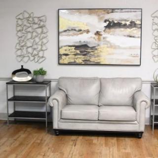 A cozy living room featuring a light-colored sofa, abstract artwork, and decorative shelves.