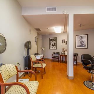 A cozy salon interior with chairs, hair dryers, and wall posters.