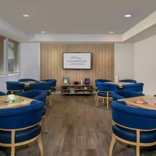 A modern lounge with blue chairs and a wall-mounted television.