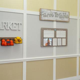 A homestyle decorated wall featuring a 'Market' sign and fruit-themed accents.