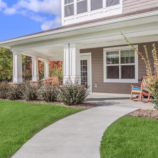 A charming suburban house with a welcoming front porch and a neatly manicured lawn.