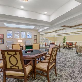 A spacious lobby area with multiple tables and chairs, featuring elegant decor and soft lighting.