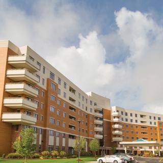 A modern multi-story apartment building with balconies under a cloudy sky.