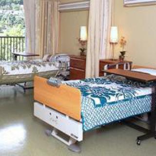 A healthcare facility room featuring two medical beds with bedside tables and curtains.