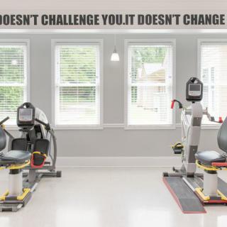 A bright gym space with exercise machines and a motivational quote on the wall.