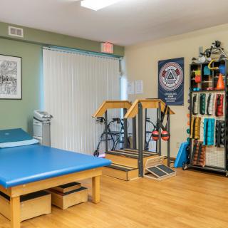 A physical therapy room equipped with a treatment bed, exercise machine, and various therapy tools.