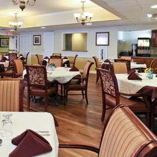 An elegant dining area with neatly arranged tables and chairs adorned with folded napkins.