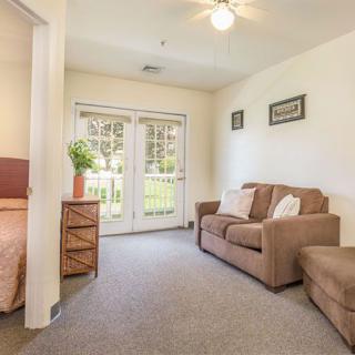 A cozy living room with a sofa and a view into an adjacent bedroom.