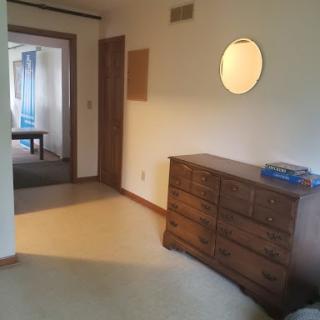 A hallway featuring a wooden dresser with a circular mirror above it.