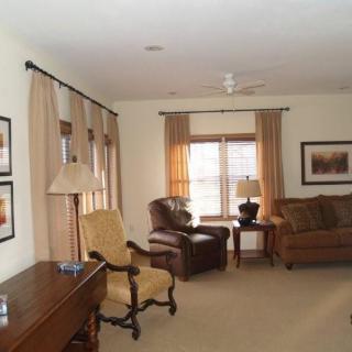 A cozy living room with a sofa, armchair, and window featuring elegant curtains.