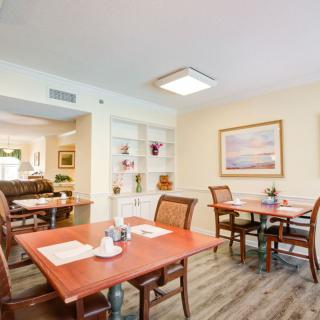 A well-lit dining room with neatly arranged tables and chairs, adorned with artwork on the walls.