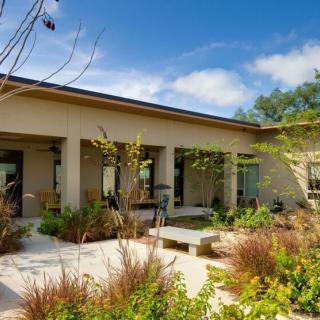 A modern house with a beautifully landscaped garden under a clear blue sky.
