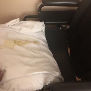 A hospital chair with stained linens.