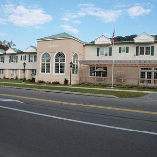 A view of a two-story building with large windows, located alongside a city road on a clear day.