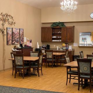 A cozy dining area with wooden tables and chairs, decorated with a chandelier and wall art.
