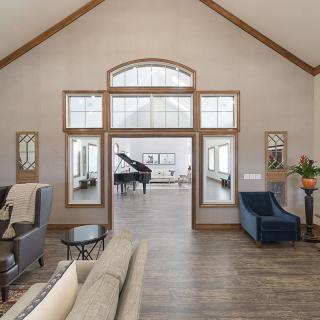 A spacious modern living room with a grand piano, featuring large windows and elegant furniture.