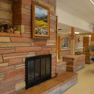 A cozy living room with a stone fireplace and framed paintings.